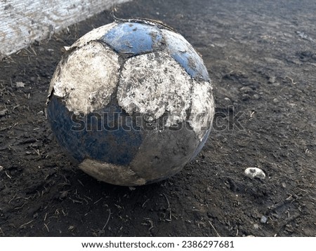 Dirty soccer ball in field with blue and white hexagons