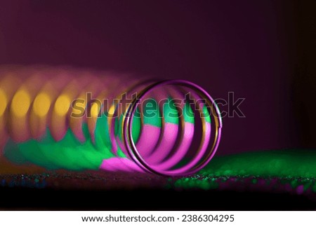 A multi-color, angular macro view of a  spring showing its spiral, tubular design.