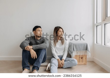 Boring and tired faces of asian lover sit on the floor of empty room.