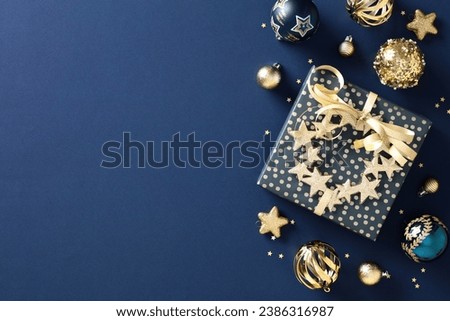 Chic navy Christmas gift box on a classic blue background with gold baubles. Elegant holiday card concept. Festive and stylish