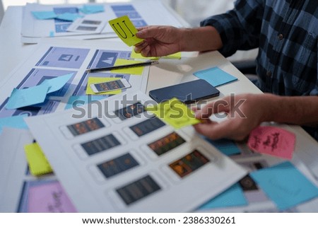 UX developers and UI designers spend more thought planning on mobile app interface design wireframe interface on desk at office creative digital concept. Royalty-Free Stock Photo #2386330261