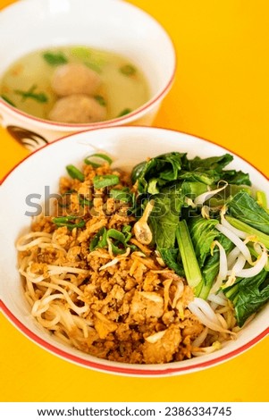 picture of Bakmi Ayam from indonesian local food stall served on top of yellow table.The soup with meatball taste delicate and rich at the same time.  