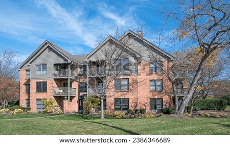 Three-story, apartment building of red brick with gray siding accents. Royalty-Free Stock Photo #2386346689
