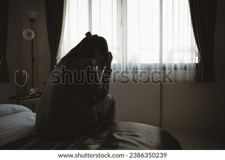 Silhouette depressed woman sadly sitting on the bed in the bedroom. Sad asian women suffering depression insomnia awake and sit alone on the bed in bedroom. Depression health people concept. Royalty-Free Stock Photo #2386350239