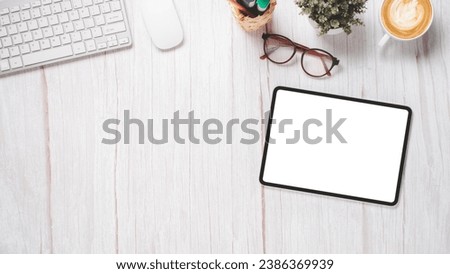 White wooden desk with blank screen tablet, keyboard, mouse, eyeglass and cup of coffee, Top view flat lay with copy space.