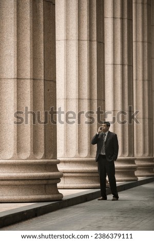 Indian businessman or Lawyer using a Smart Phone outside a colonial courthouse building. 
 Royalty-Free Stock Photo #2386379111