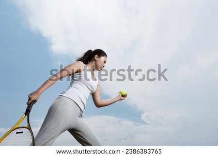 Asian Woman playing tennis getting ready to serve the ball. Royalty-Free Stock Photo #2386383765