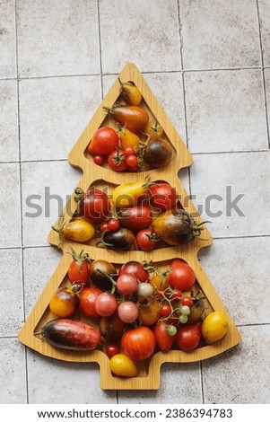 organic ripe colorful tomatoes on a wooden board in the shape of a Christmas tree on the table