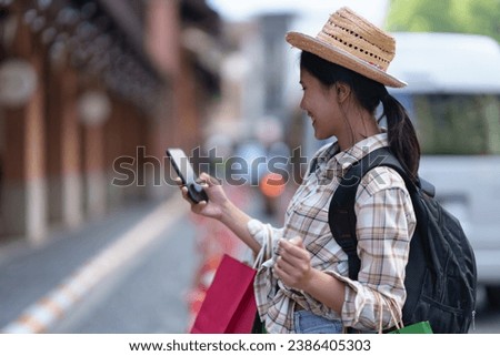 Young Asian tourists hold smartphones to take photos, chat online, have a drink to relax. Looking for a beautiful area Important tourist attractions at various points, relaxation concepts, lifestyle.