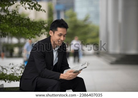 Asian business man talking reading his smart phone. Royalty-Free Stock Photo #2386407035