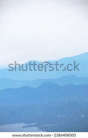 Parachute on blue color gradient background. Paragliding taking off from Fethiye Babadağ. Color transitions. Freedom feeling idea concept. Alone. Vertical photo. Extreme sport. Nature.