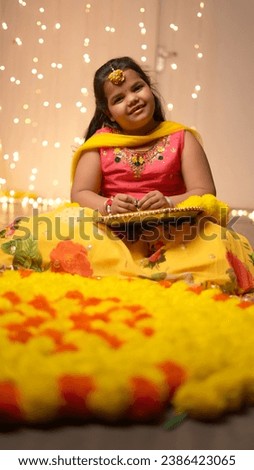 Happy Indian kid girl celebrating diwali,holding giftboxes,making rangoli