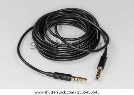Rolled up analog audio cable with gold-plated stereo connectors mini jack on the edges on a gray surface, close-up in selective focus
 Royalty-Free Stock Photo #2386433545