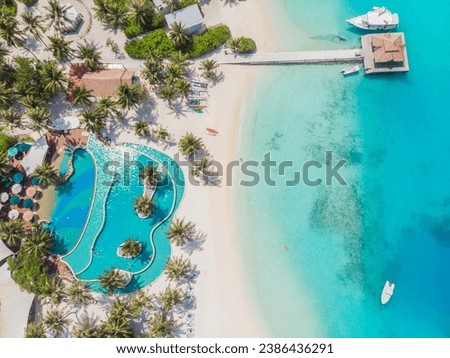 View from a flying drone. Aerial top view of Luxury tropical resort pool with palm trees against the background of the beauty of the sea with coral reefs. Aero Photography 