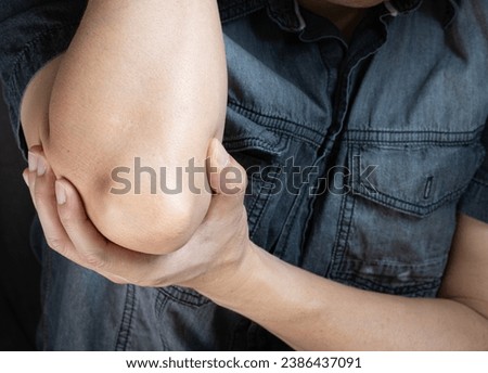 A man has pain in his elbow and tendon muscles and he relieves the pain with a massage. Health and healing concept