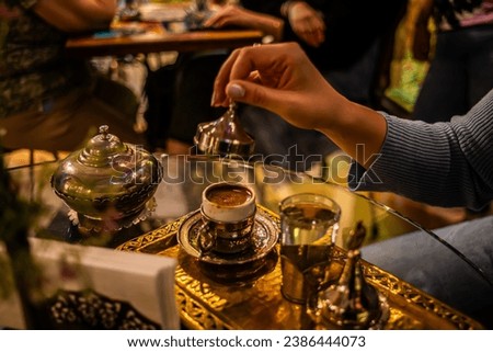 Graceful moment captured: a girl delicately opening the cap of a traditional Turkish coffee cup. Limited edition, this image preserves the art of coffee ritual in Istanbul. Royalty-Free Stock Photo #2386444073