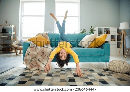 Full size photo of overjoyed cheerful lovely girl sit sofa upside down have good mood spend free time modern flat indoors