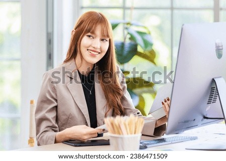 Portrait closeup shot Asian professional successful young female businesswoman creative graphic designer in casual fashionable suit outfit sitting smiling working with computer at workstation desk.
