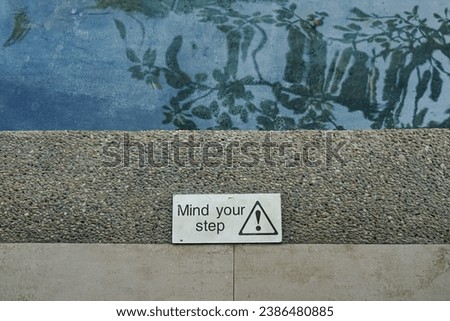 Mind your step sign on the floor near a pool