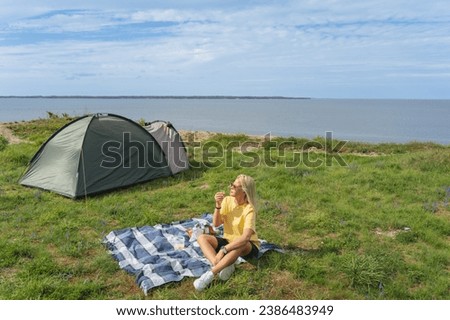 A girl on a picnic near a tent in nature by the sea on the cliff of Paldiski in the summer. High quality photo