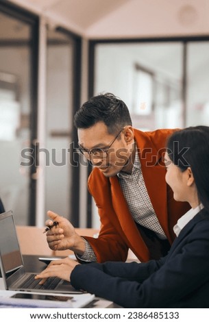 Four asian people in an office, working together on laptops, discussing tasks. annual gathering where attendees share and discuss opinions, presentation teamwork group meeting laptop in boardroom Royalty-Free Stock Photo #2386485133