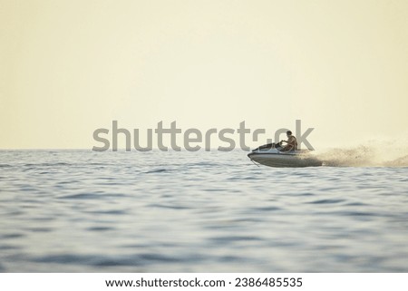 Adventurous Person Speeding on a fast water bike  Jet Over Calm Sea Waters at Golden Hour Royalty-Free Stock Photo #2386485535