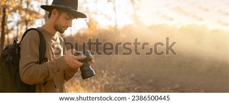 Young outdoor photographer photographing sunset in autumn in the forest. Banner. Copy space