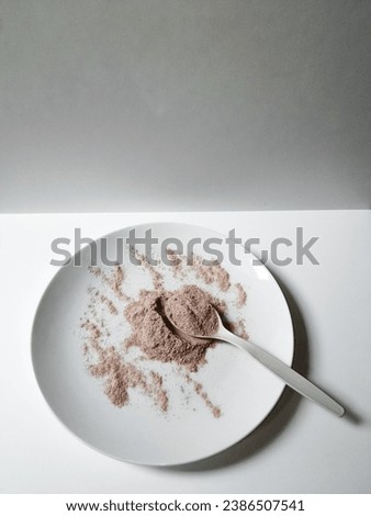 Pile of fresh ground coffee latte and spoonful of coffee latte powder on a white plate isolated on white background