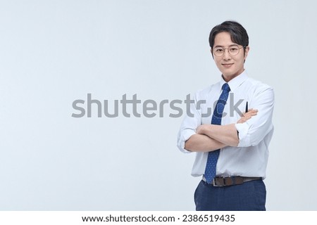 A young, handsome Asian man wearing glasses and a dress shirt and tie is holding a pen and explaining about business. Royalty-Free Stock Photo #2386519435