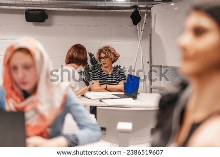 Middle-aged businesswoman working together with her young female colleague on a new project. Learning, discussing, sharing knowledge, junior, senior, project work.