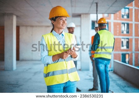 Female construction engineer is using digital tablet on the construction site. Young female worker using her digital tablet at a construction site. Woman with plan, digital tablet.
