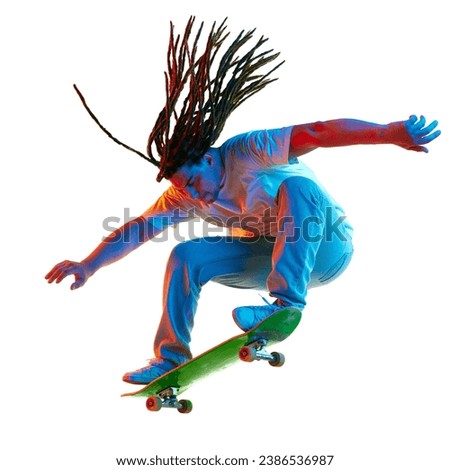 Young man, skateboarder with modern hairstyle practicing Ollie on skateboard in neon light isolated white background. Concept of youth culture, active lifestyle, style and fashion, creativity, art.