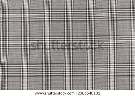 The texture of a black and brown tartan checkered fabric. Material for sewing skirts, shirts and clothes. Background for your mockup. Traditional Scottish clothing. Royalty-Free Stock Photo #2386540181