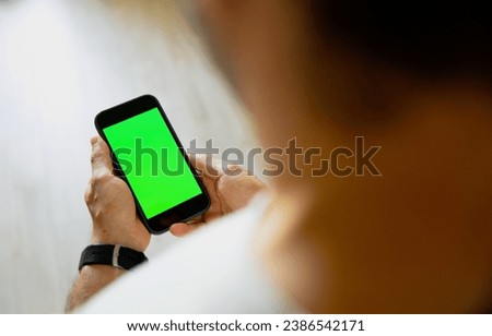Some person is holding a phone with a green screen in his hands. Using chromakey on your phone screen. Place for text, pictures. Business, finance, training.