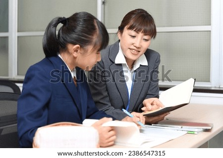 Young female teacher teaching female students studying
 Royalty-Free Stock Photo #2386547315
