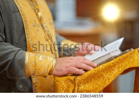 The hands of an Orthodox priest hold a bible Royalty-Free Stock Photo #2386548559