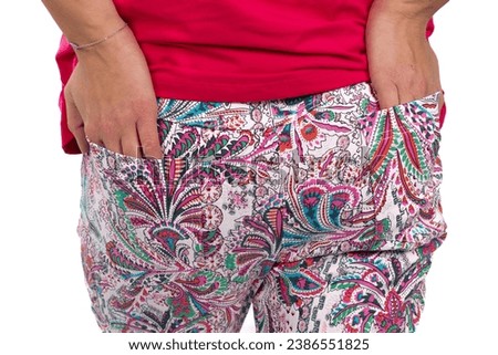 A close-up image captures a woman's hands comfortably tucked into the back pockets of her colorful patterned pants Royalty-Free Stock Photo #2386551825