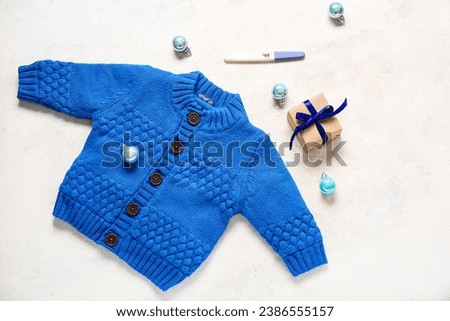 Composition with baby clothes, pregnancy test and Christmas balls on light background