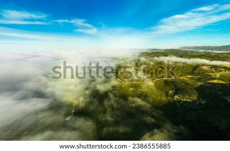 Sea of mist over mountain. Beautiful top mountain view with sea of mist. Fog over mountain. Aerial panoramic drone shot. Aerial view Panorama of flowing fog waves on mountain. 