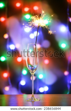 Beautiful sparkler in glass on shiny background, close up