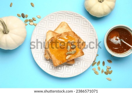 Plate of toasts with sweet pumpkin jam and seeds on blue background