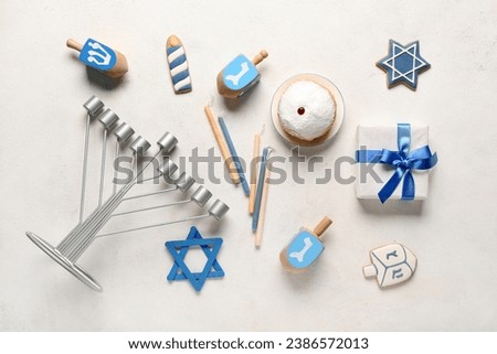 Hannukah composition with menorah, candles, donut and dreidels on white table Royalty-Free Stock Photo #2386572013