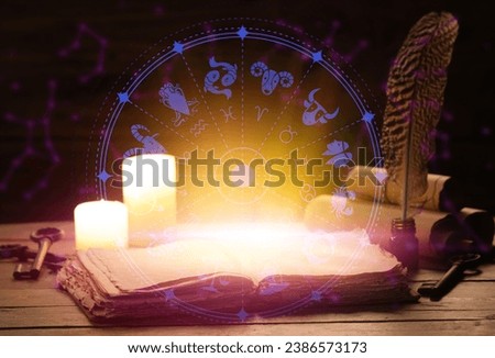 Open book, candles and astrological signs on table against dark background Royalty-Free Stock Photo #2386573173