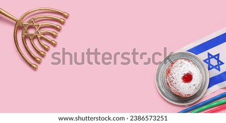 Hanukkiah, traditional donut and flag of Israels with candles on pink background with space for text. Hannukah celebration