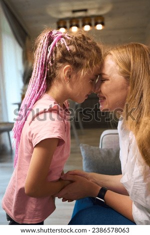 Lovely mother and little daughter with pink braids rubbing nose to nose