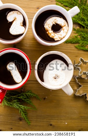Cups with hot chocolate garnished with white marshmallows on wood table.