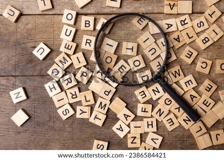 Magnifying glass with many wood letters of English alphabets, learning English concept.