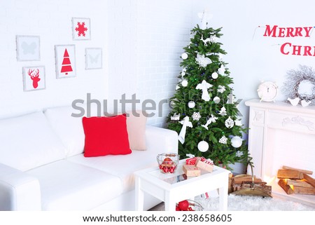Beautiful Christmas interior with sofa, decorative fireplace and fir tree
