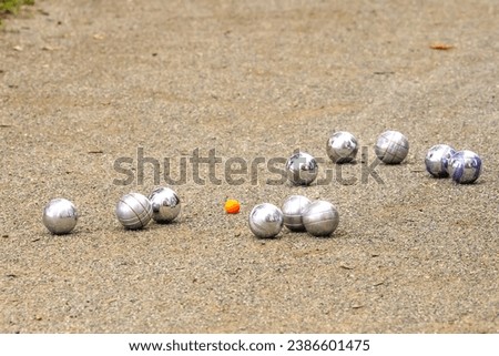 Precision Boules Games: Pétanque, Boccia, Boule Lyonnaise and Jeu Provençal with silver bowls and red ball on dandy ground. Royalty-Free Stock Photo #2386601475