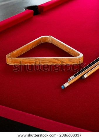 Close-up of red pool table, triangle rack, and cue sticks Royalty-Free Stock Photo #2386608337